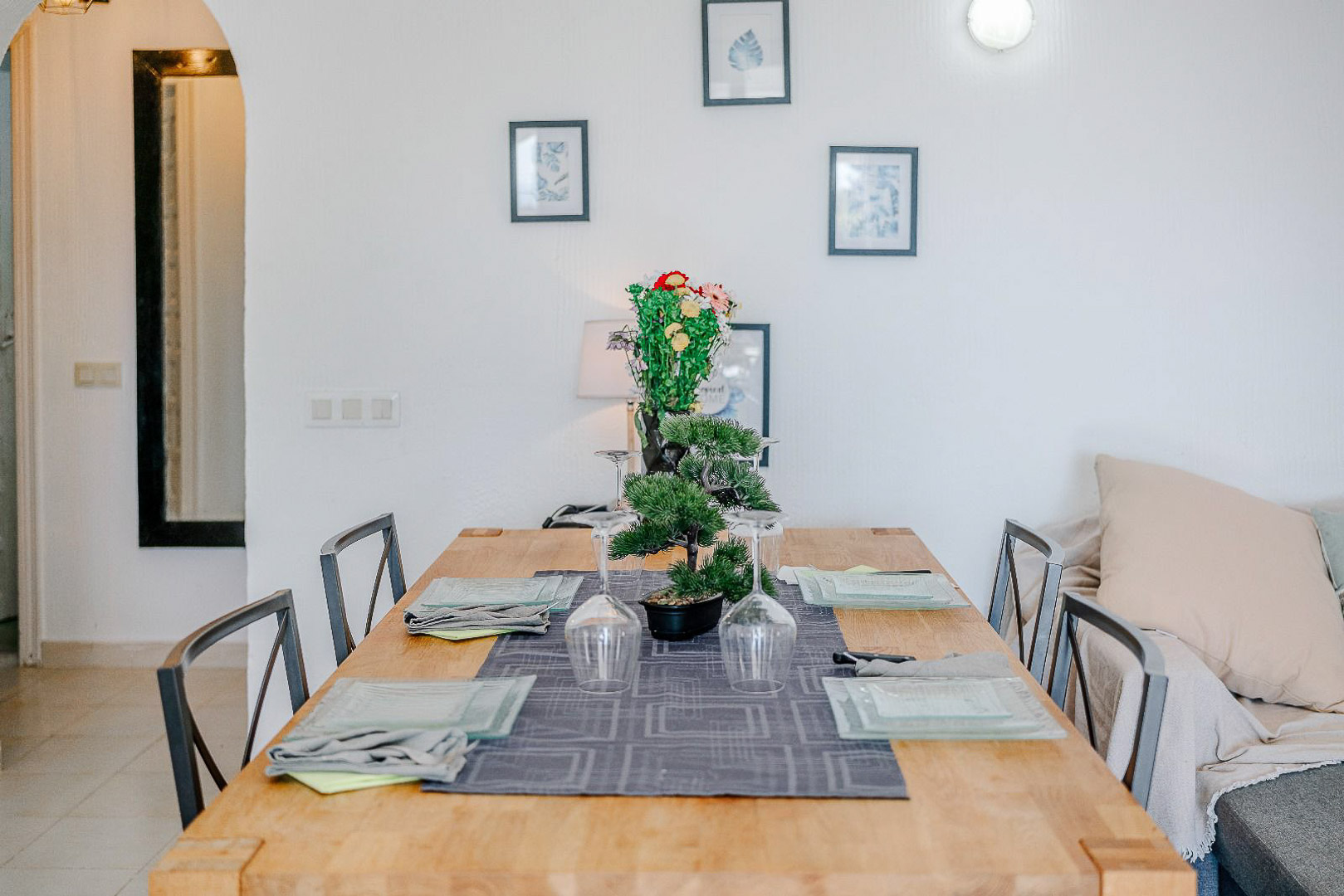 Eethoek met een licht houten tafel en metalen stoelen, verfijnd gedecoreerd met glaswerk en wandkunst nabij een karakteristieke ronde toog.