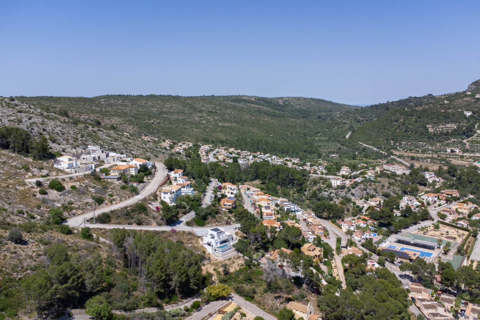 Panoramisch luchtfoto van Residencial VALL DE POP in Alcalalí, met de verhoogde ligging van de percelen en de integratie in het natuurlijke landschap van de vallei.