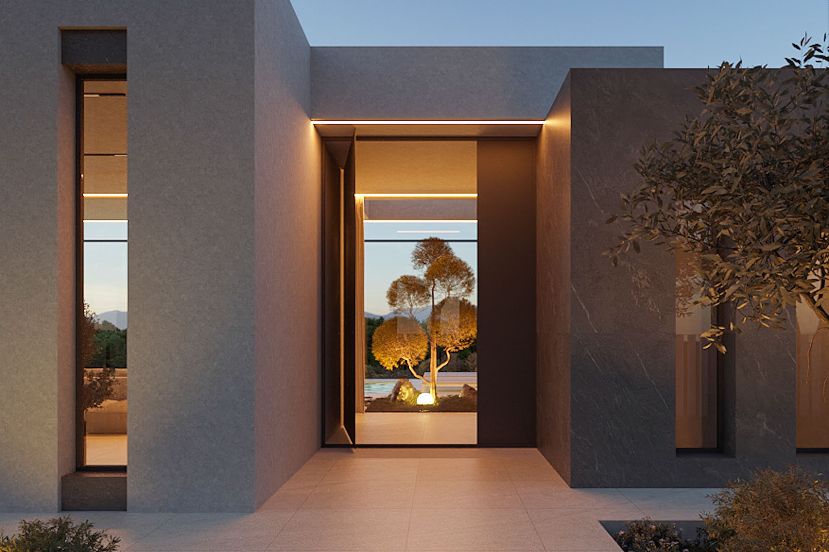 Minimalistische hoofdingang met grijze natuurstenen gevel, geïntegreerde LED-verlichting en doorkijk naar de verlichte mediterrane tuin.