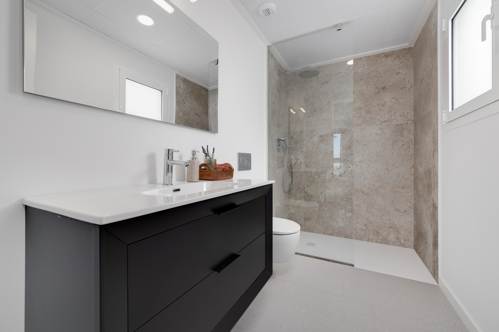 Moderne badkamer met zwart wastafelmeubel, inloopdouche met wandtegels in steenlook en strakke chromen kranen.