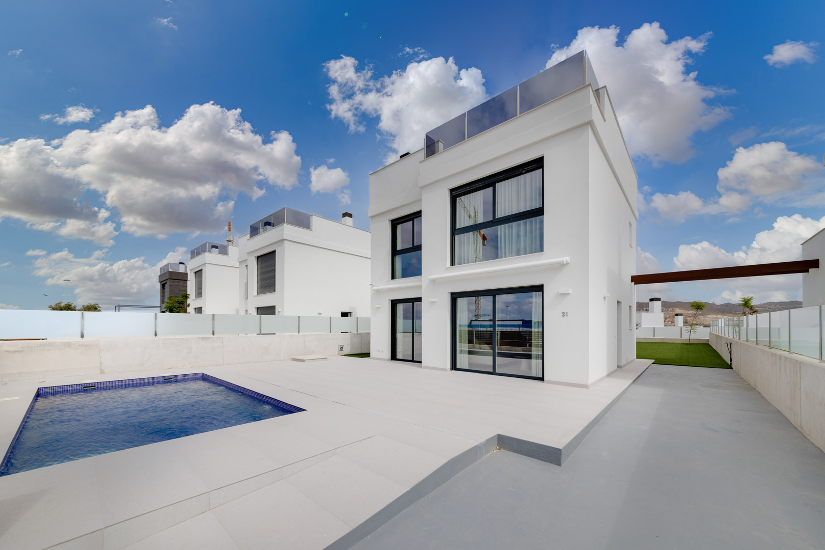 Moderne witte villa met een rechthoekig privézwembad, ruim betegeld terras en grote minimalistische raampartijen.