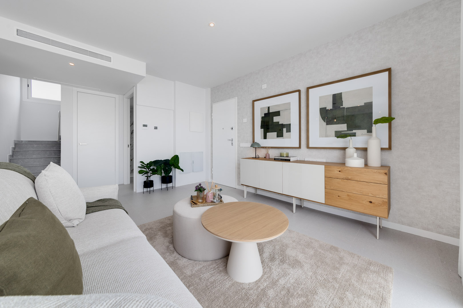 Moderne woonkamer met een minimalistisch dressoir, abstracte kunst en een zithoek in neutrale tinten met natuurlijke houten accenten.