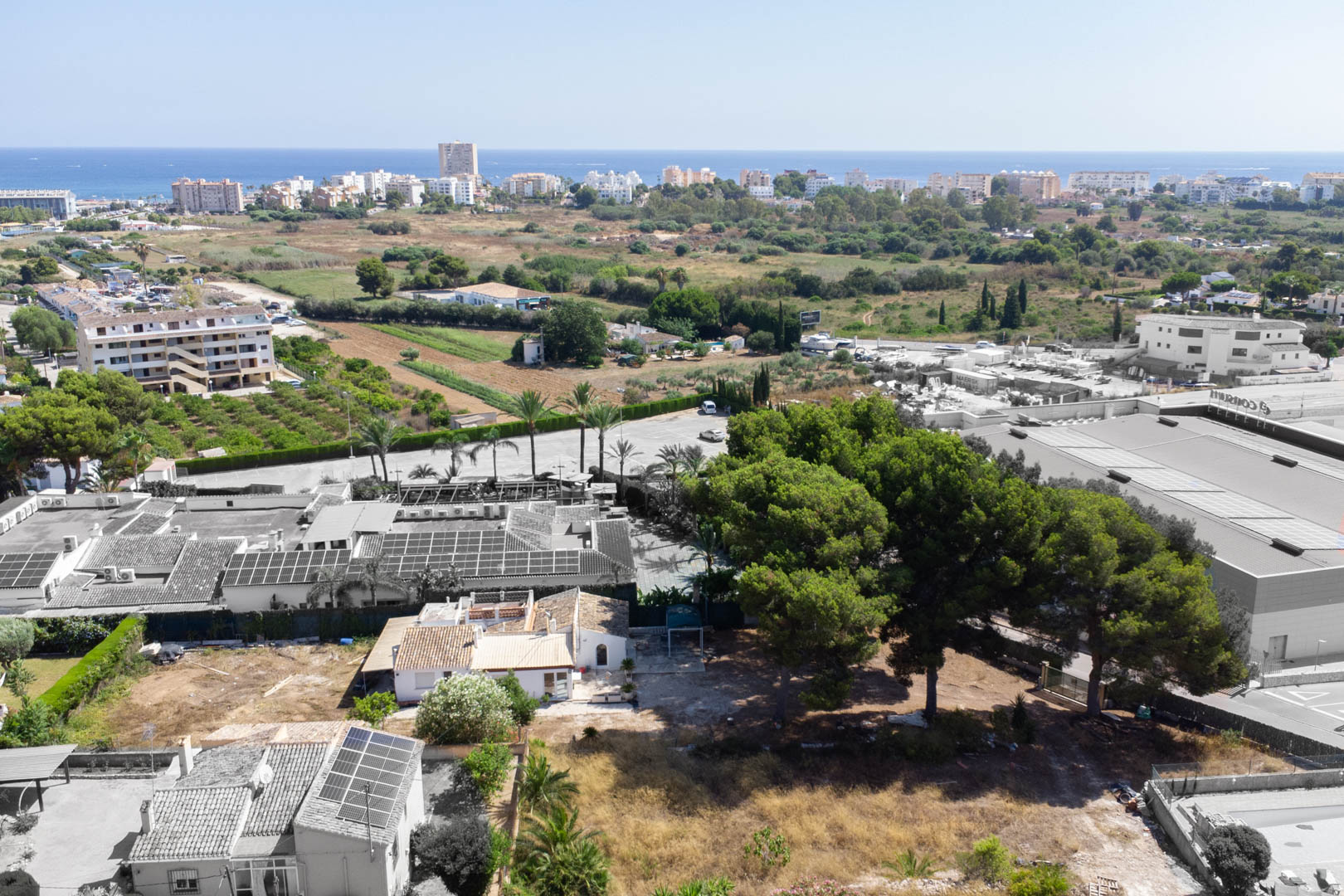 Luchtfoto van het perceel van 2.600 m² in Jávea, met de bestaande villa, volwassen pijnbomen en de gunstige ligging nabij de Middellandse Zee.