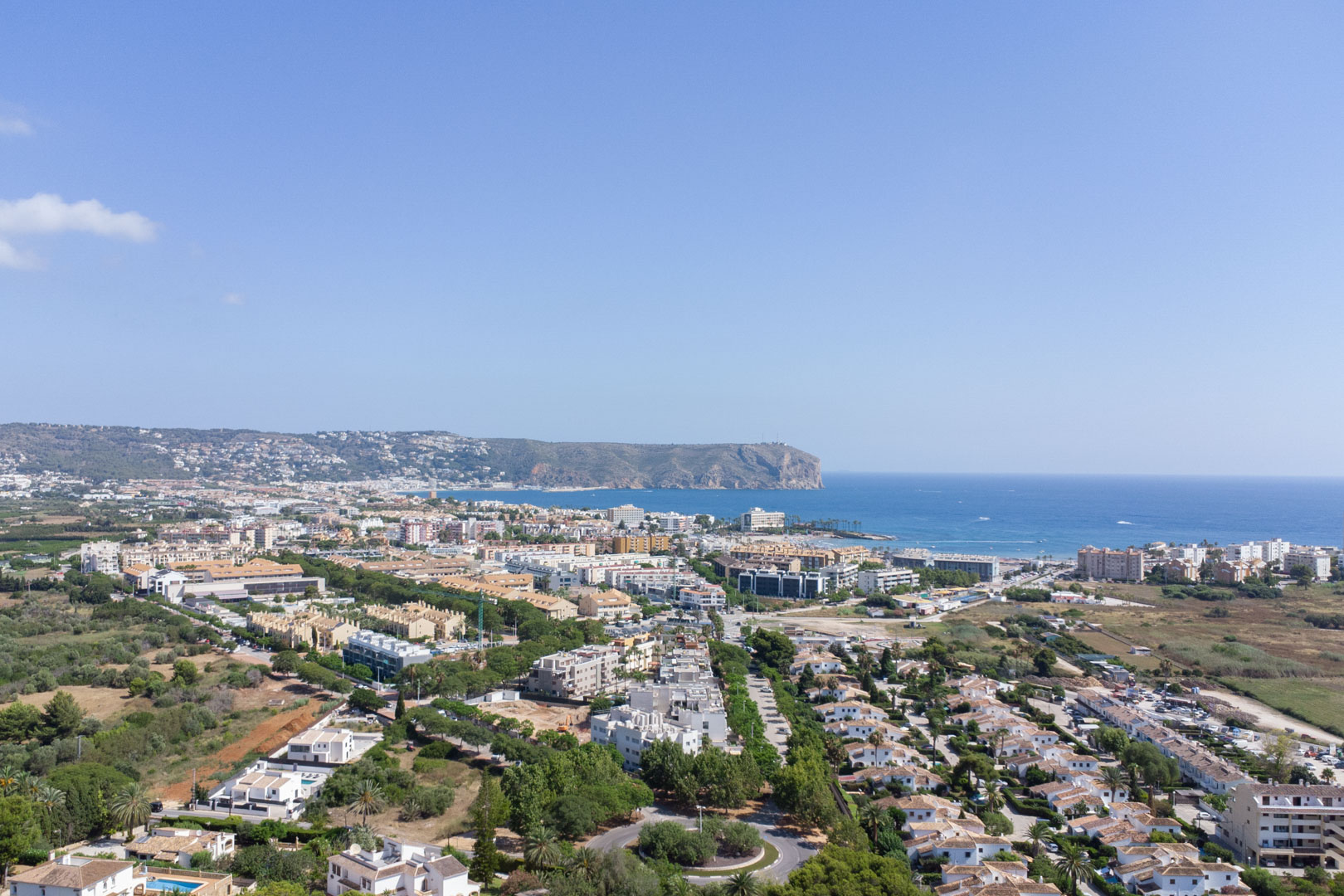 Panoramisch luchtfoto van Jávea met uitzicht op de Middellandse Zee en de iconische Cabo de San Antonio onder een heldere hemel.