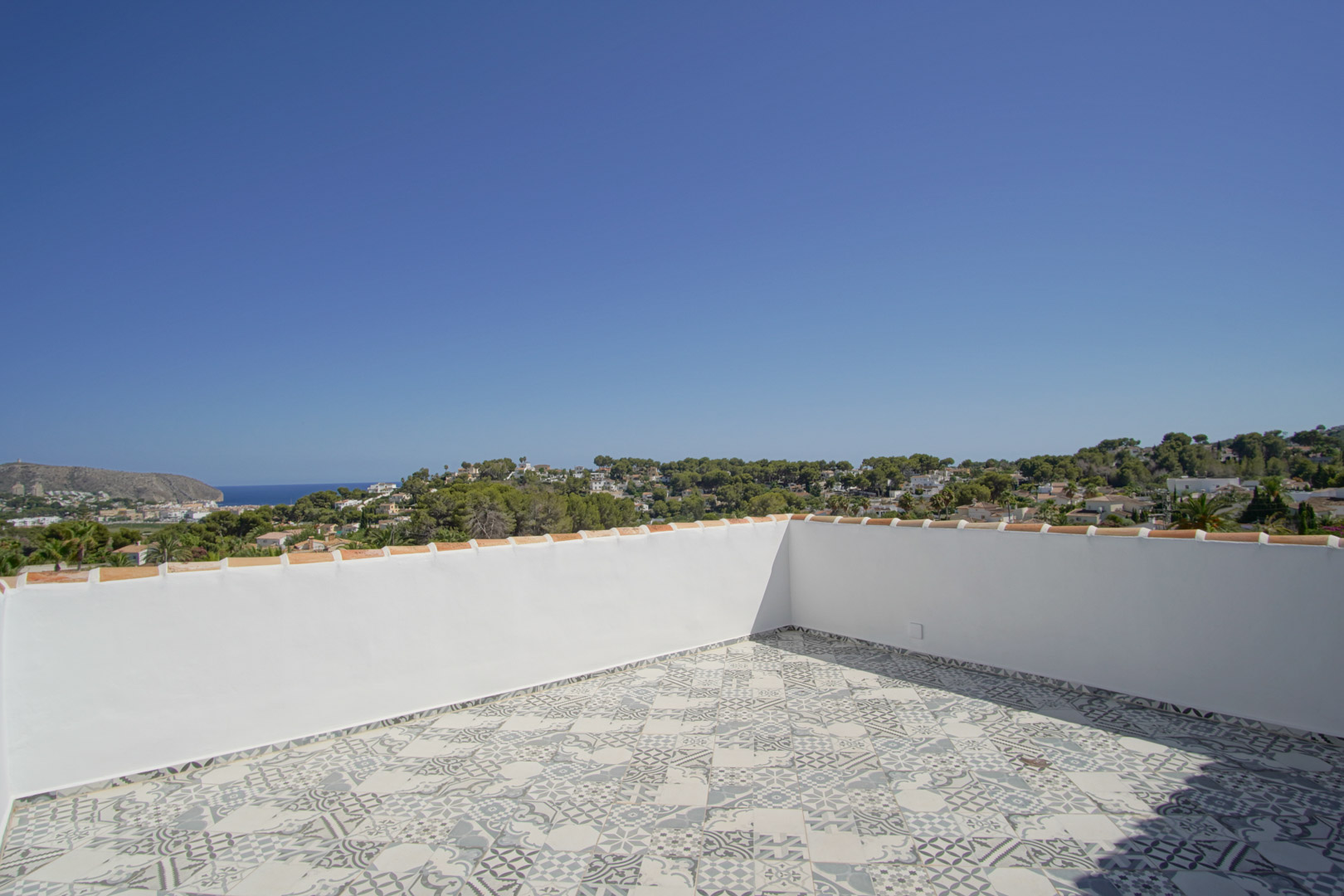 Dakterras met gedecoreerde keramische tegels en panoramisch uitzicht over de Middellandse Zee, de kust van Moraira en de omliggende groene heuvels.