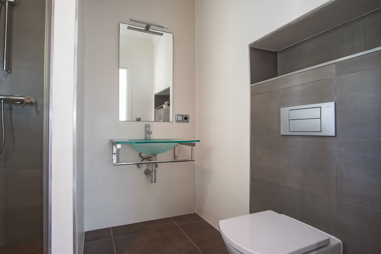Moderne badkamer met hangend toilet, een wastafel van matglas op een chromen onderstel en getextureerde wandtegels met een ingebouwde nis.