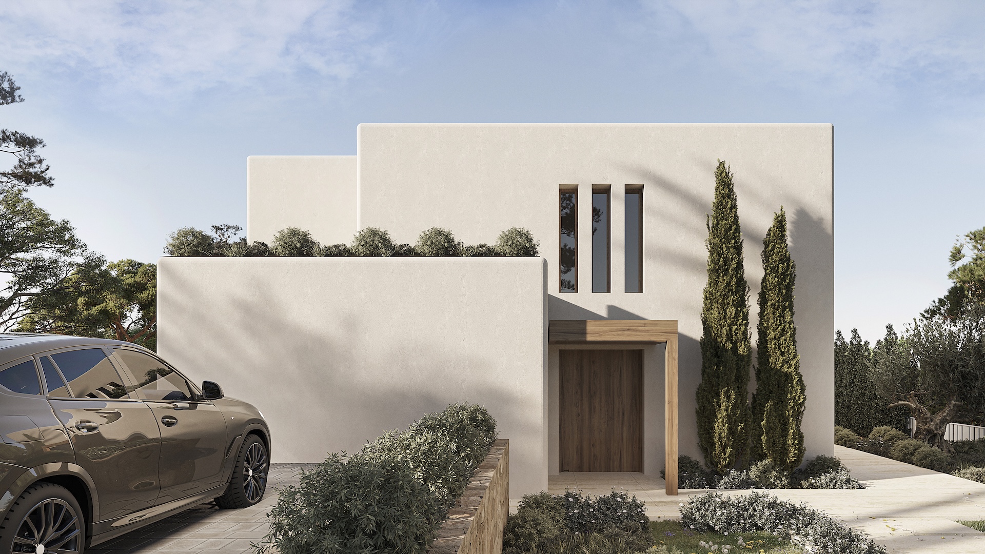 Hoofdgevel in Ibizastijl met witte structuurmuren, een houten toegangsdeur onder een latei en smalle verticale vensters. De oprit is voorzien van stenen bestrating en cipressen.