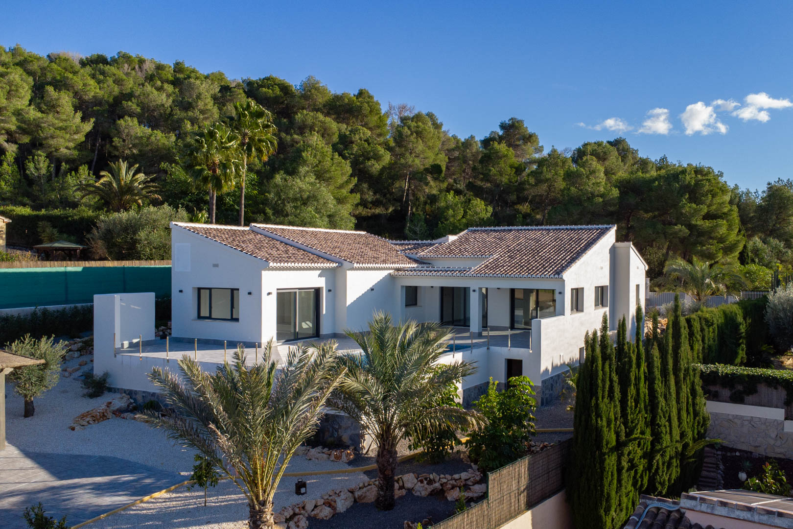 Buitenaanzicht van de nieuwe villa in Jávea, met de nadruk op het moderne design en het privézwembad omgeven door weelderig groen.