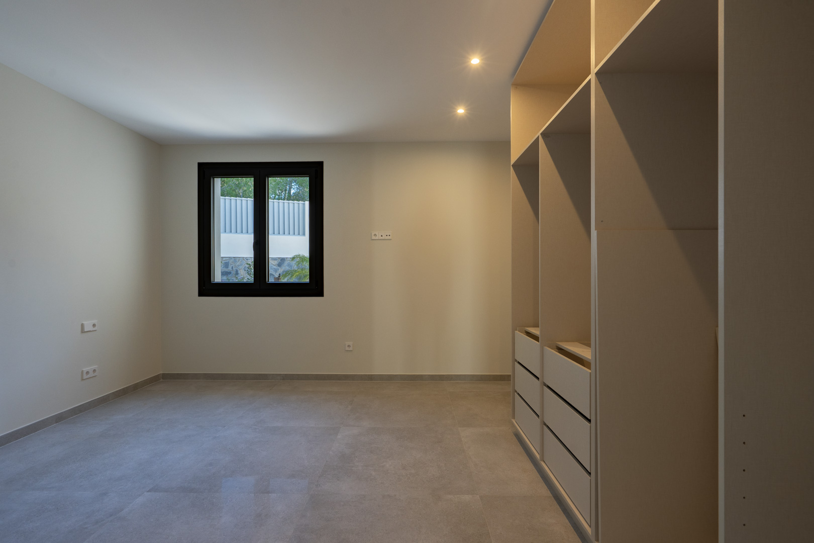Licht interieur met inbouwkast en zwartomlijst raam.