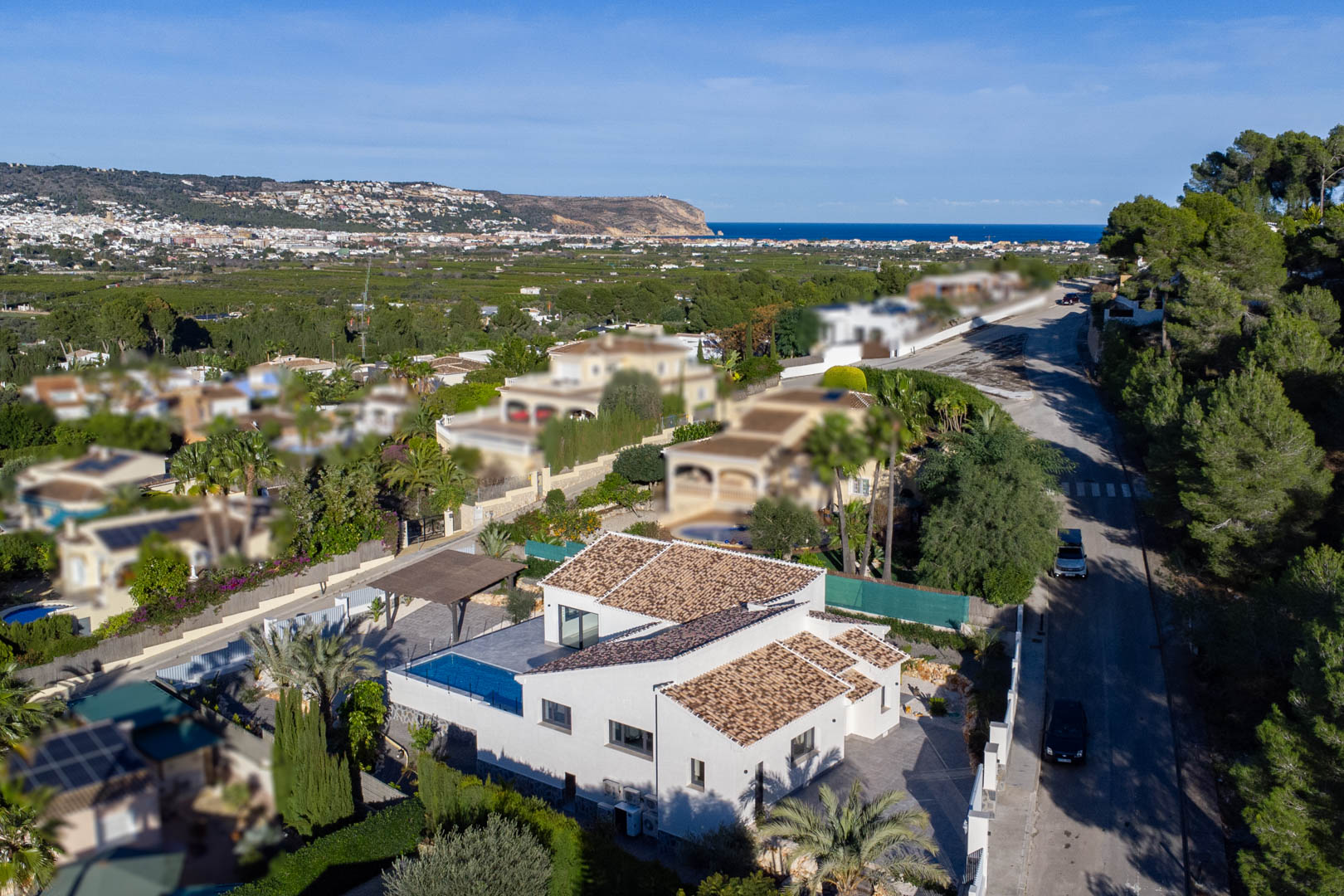 Luchtfoto van moderne villa met zwembad in Jávea, omgeven door tuinen en uitzicht op zee.