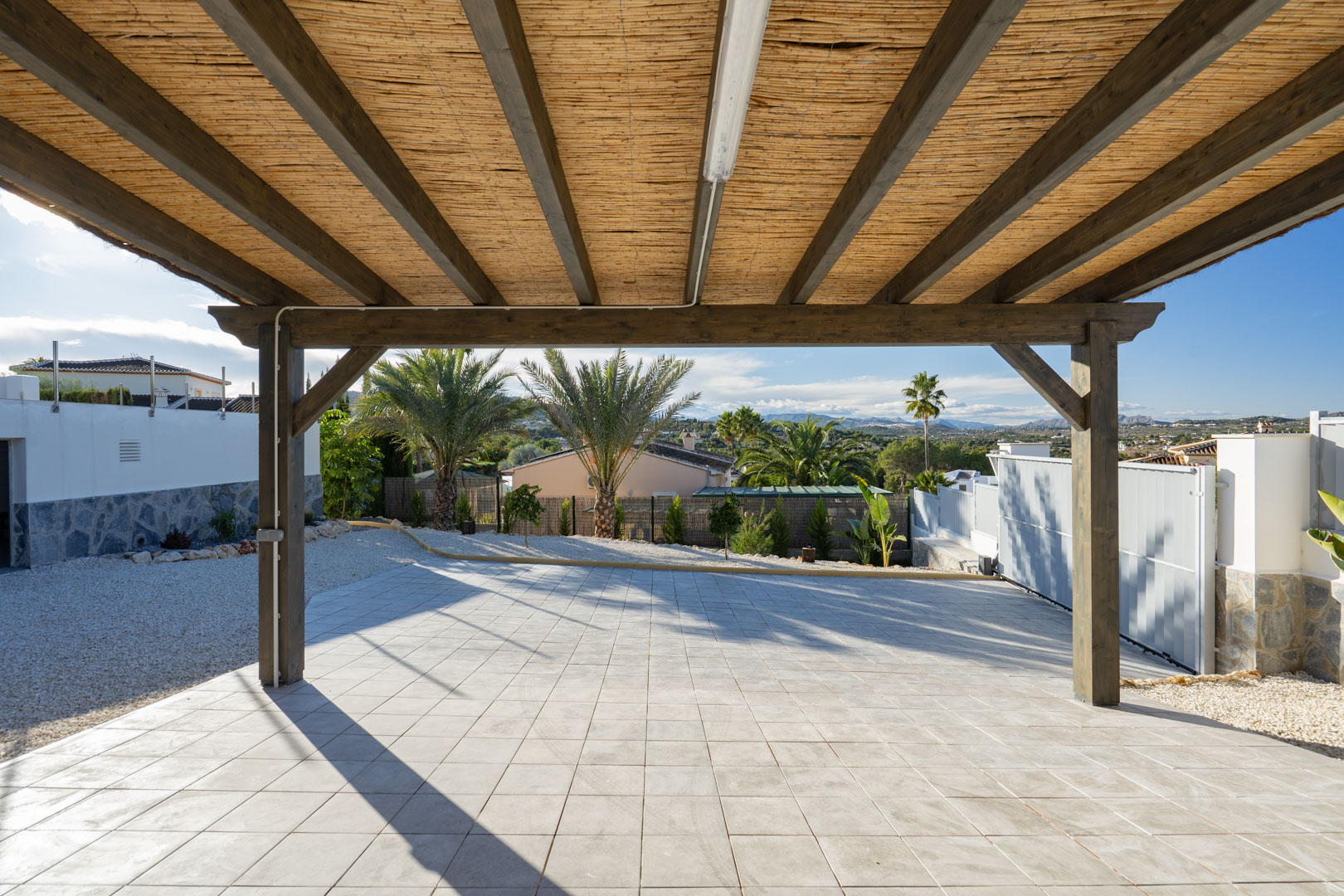 Pergola met houten structuur en rieten dak, boven betegelde vloer in villa in Jávea.