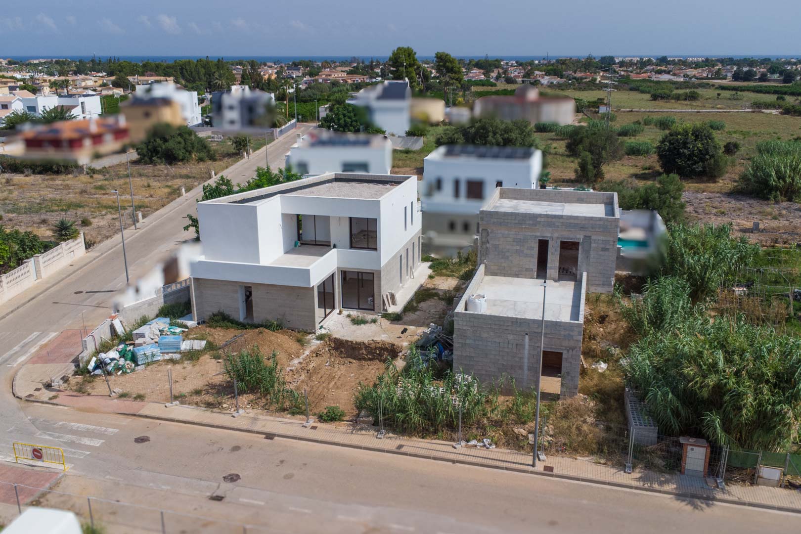 Luchtfoto van het woonproject in El Vergel, met twee moderne villa's in aanbouw met witte gevels en vrij uitzicht op de Middellandse Zeekust.
