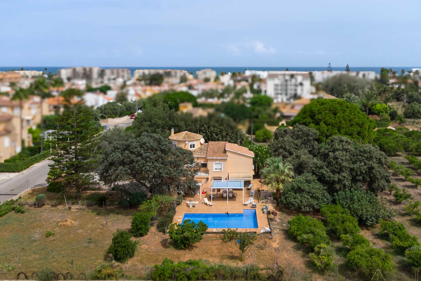 Luchtfoto van de mediterrane villa in Las Marinas, met een groot vlak perceel, zwembad, schaduwrijke terrassen en uitzicht op zee in de verte.