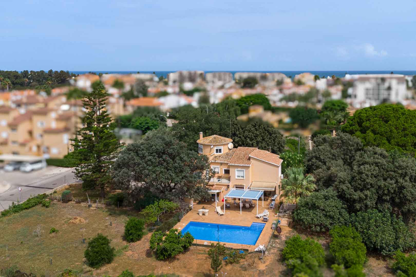 Luchtfoto van de mediterrane villa met privézwembad, schaduwrijke terrassen en een uitgestrekt vlak perceel met volwassen bomen nabij de kust van Dénia.