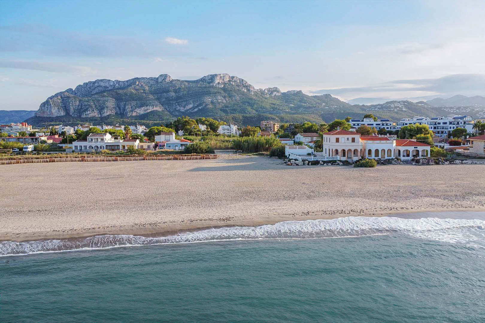 Luchtfoto van het strand van Las Marinas met de Montgó op de achtergrond, die de directe ligging aan zee en het uitgestrekte zandstrand van Dénia benadrukt.