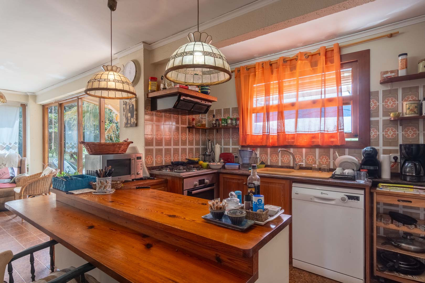 Rustieke keuken met massief houten bar, traditionele wandtegels en decoratieve hanglampen. De ruimte is voorzien van diverse inbouwapparatuur.
