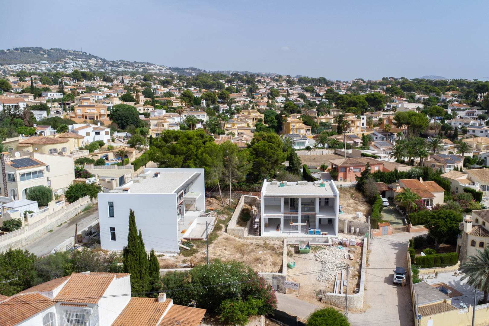 Luchtfoto van de moderne villa in aanbouw, met de witte gevel en het vlakke perceel in de residentiële wijk van Calpe.