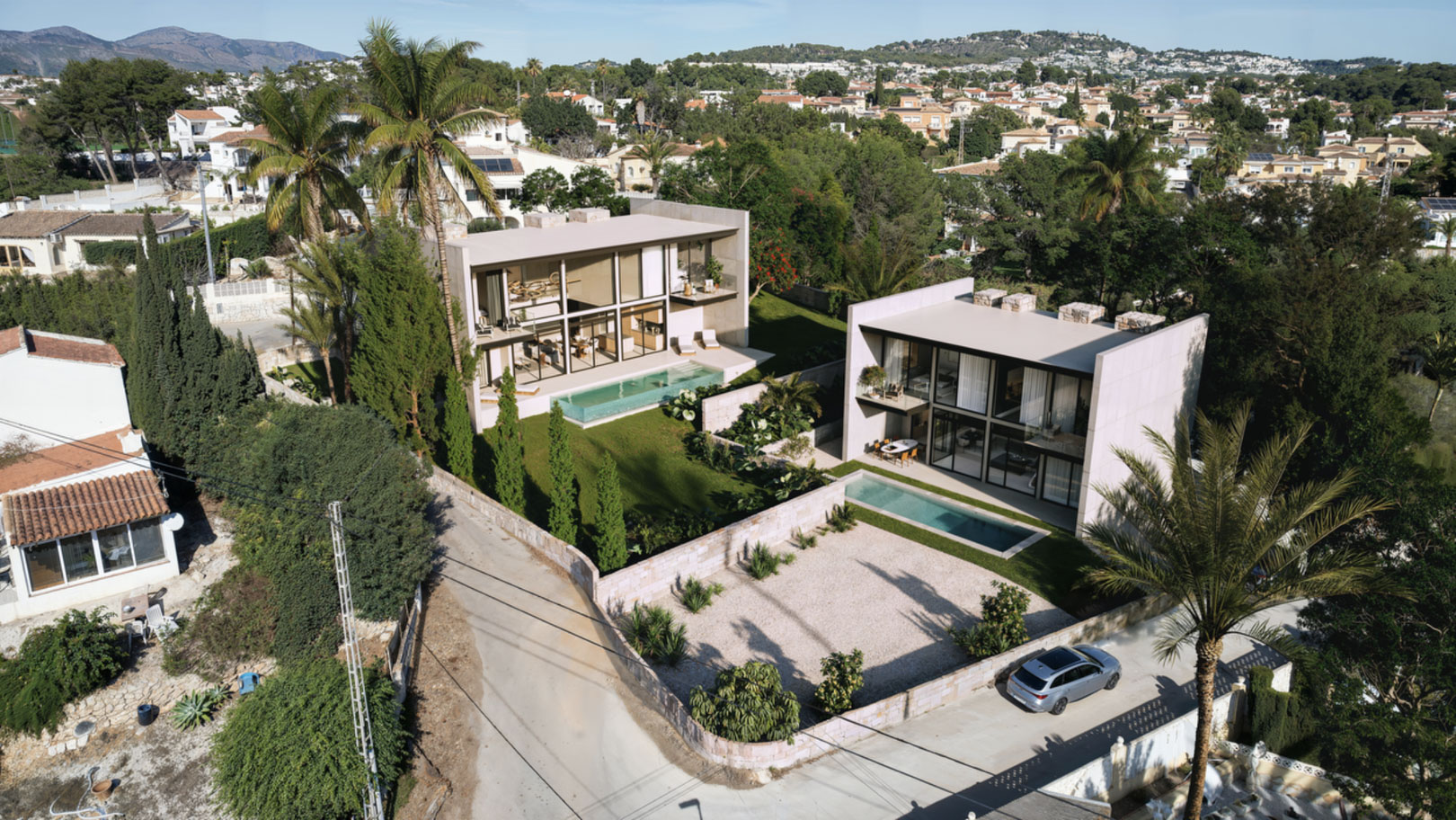 Luchtfoto van twee moderne villa's met glazen gevels, privézwembaden en mediterrane tuinen in een rustige woonwijk in Calpe.
