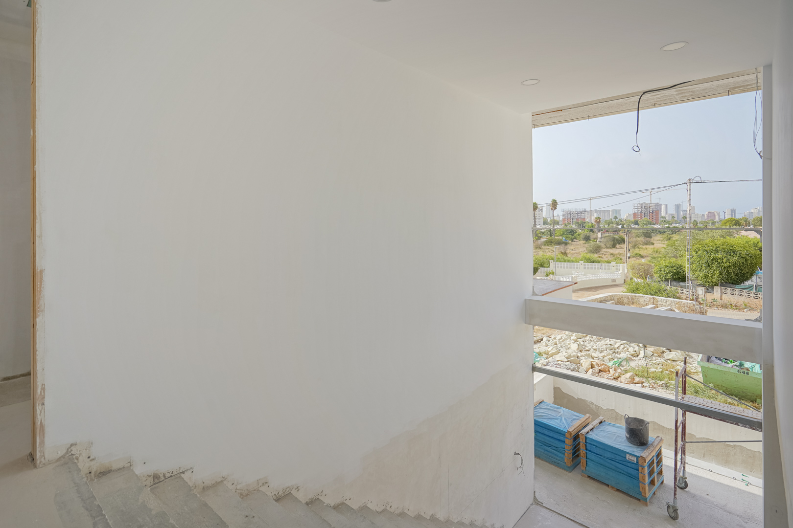 Uitzicht vanaf de onafgewerkte trap op de grote raampartij en de skyline van Calpe tijdens de huidige bouwfase van de villa.