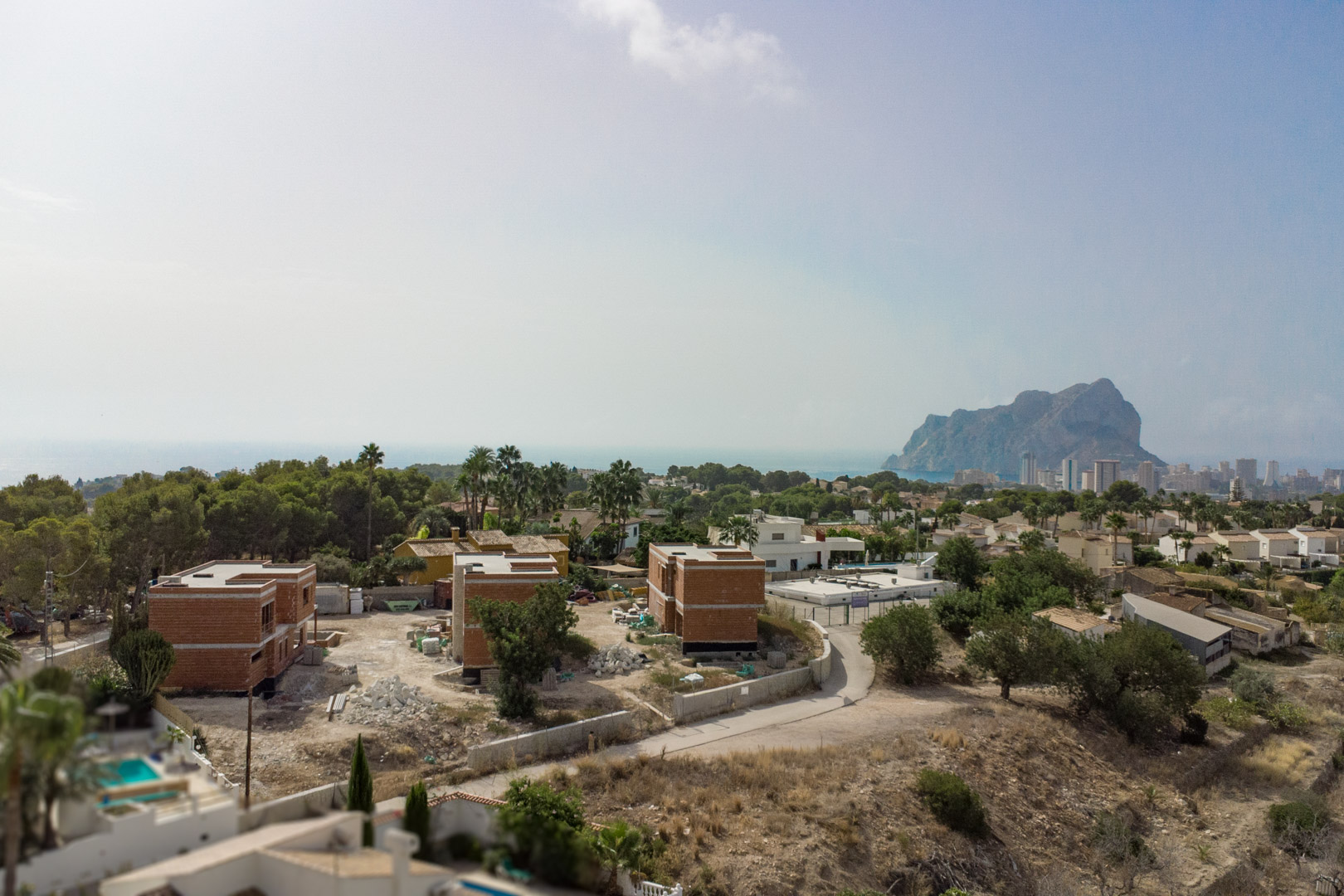 Luchtfoto van de drie villa's in aanbouw in Partida Gran Sol, met uitzicht op de Peñón de Ifach en de skyline van Calpe aan de Middellandse Zee.