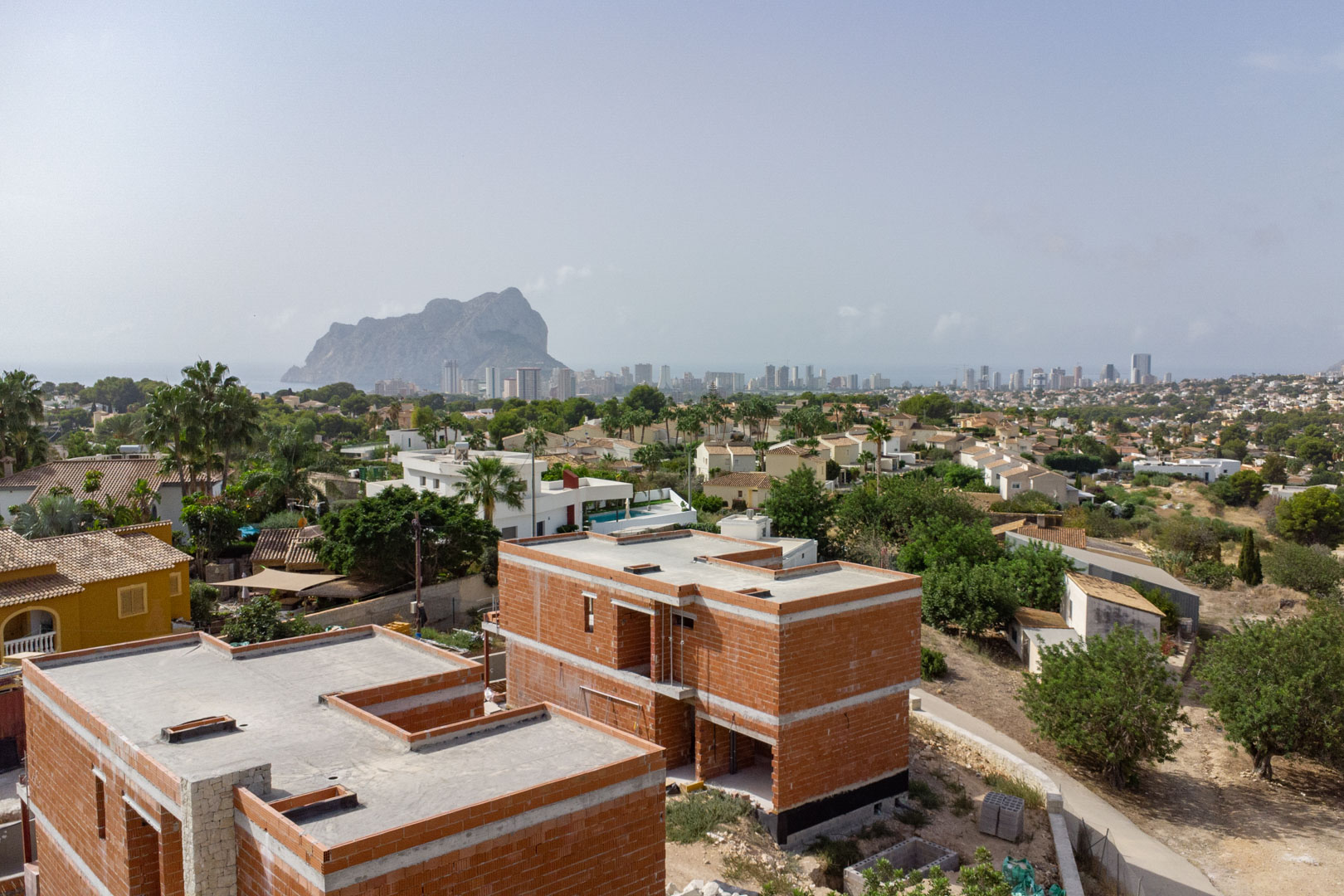 Luchtfoto van de ruwbouwfase van de villa's, met een panoramisch uitzicht op de Peñón de Ifach en de skyline van Calpe.