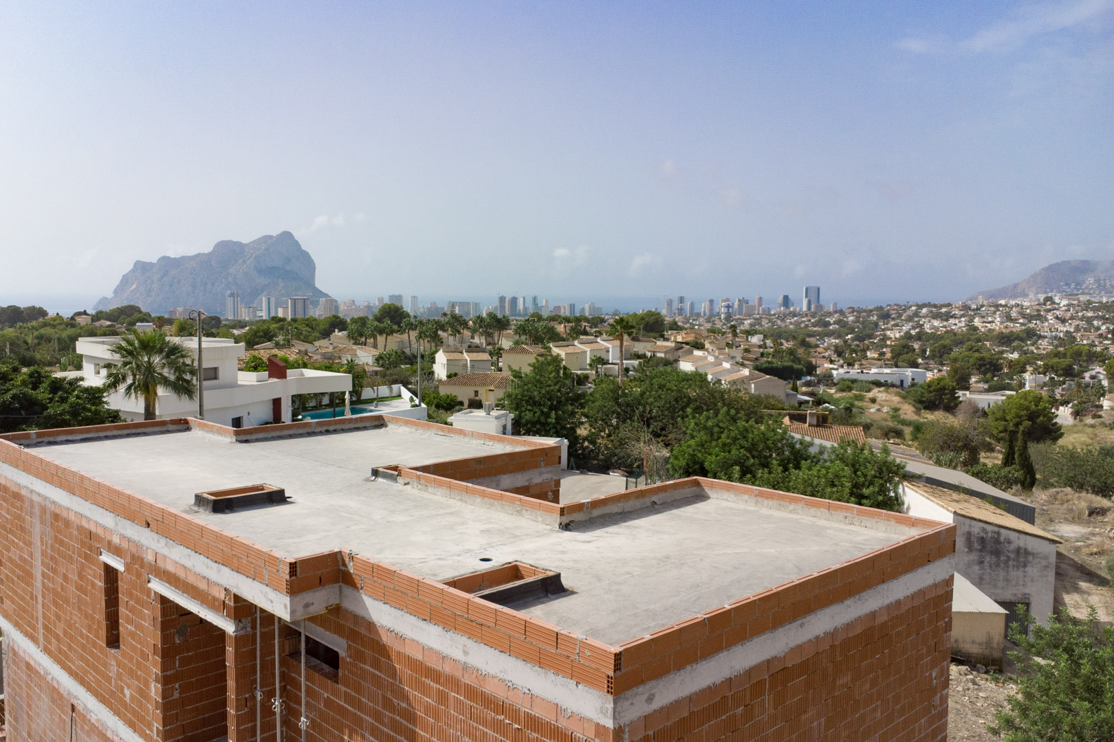 Uitzicht vanaf de ruwbouw op de skyline van Calpe en de Peñón de Ifach, wat de gunstige ligging en de voortgang van de constructie illustreert.