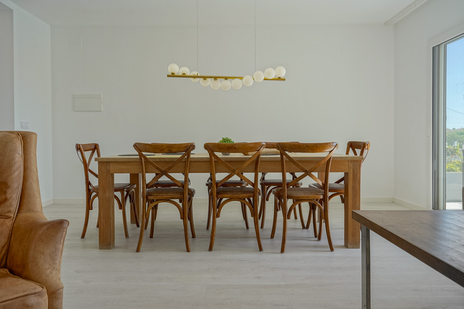 Eethoek met een massief houten tafel, kruisrugstoelen en een moderne hanglamp, gelegen op een lichte laminaatvloer.