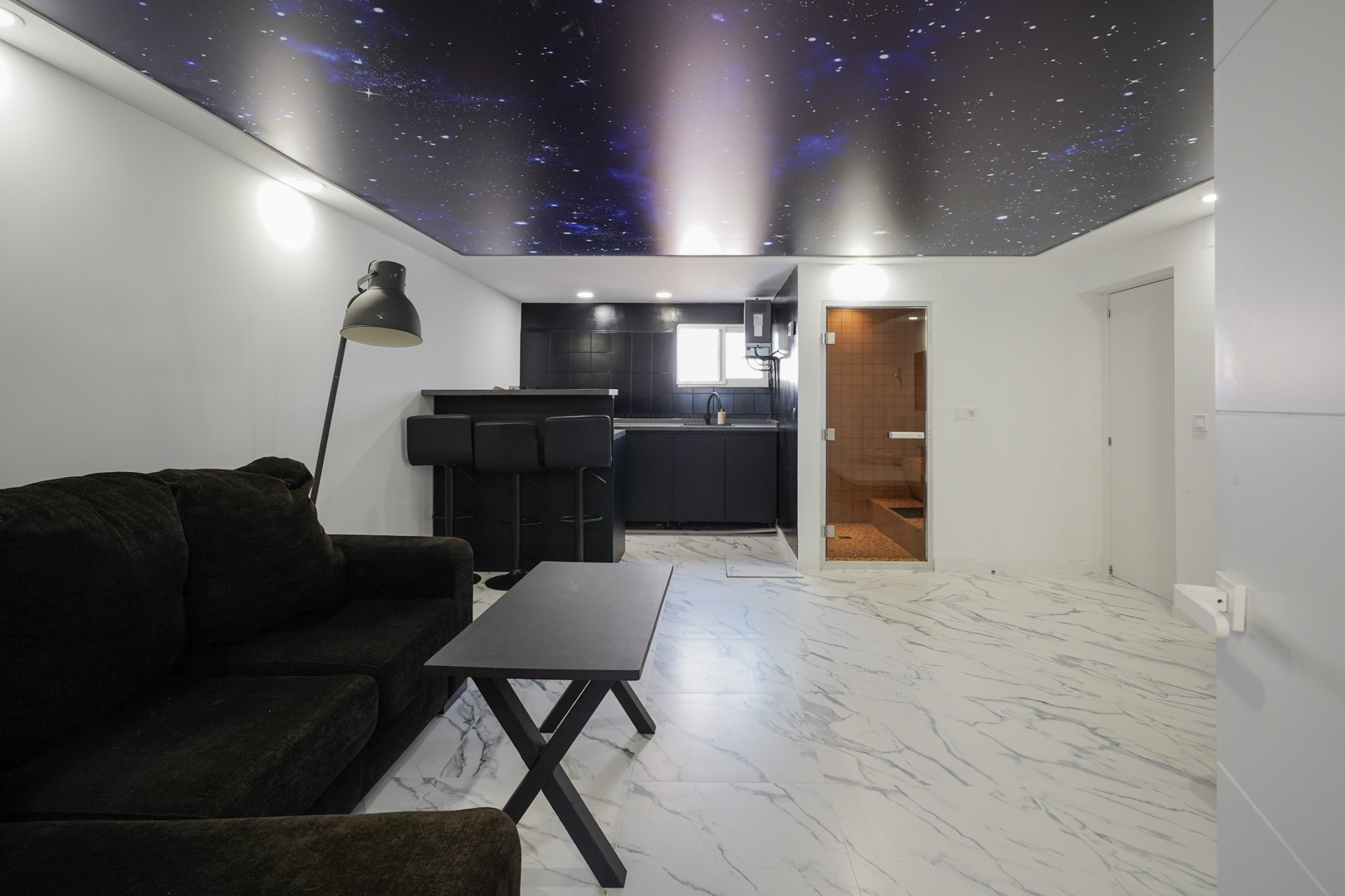 Verblijfsruimte met kitchenette, marmerlook vloertegels, een uniek sterrenhemel-spanplafond en toegang tot een geïntegreerde privésauna.