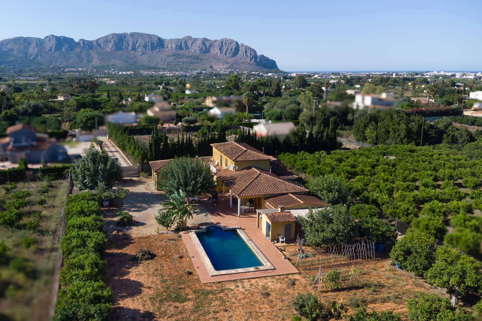 Luchtfoto van de villa met terracotta dakpannen, privézwembad en uitgestrekte citrusboomgaarden met uitzicht op het Segaria-gebergte.