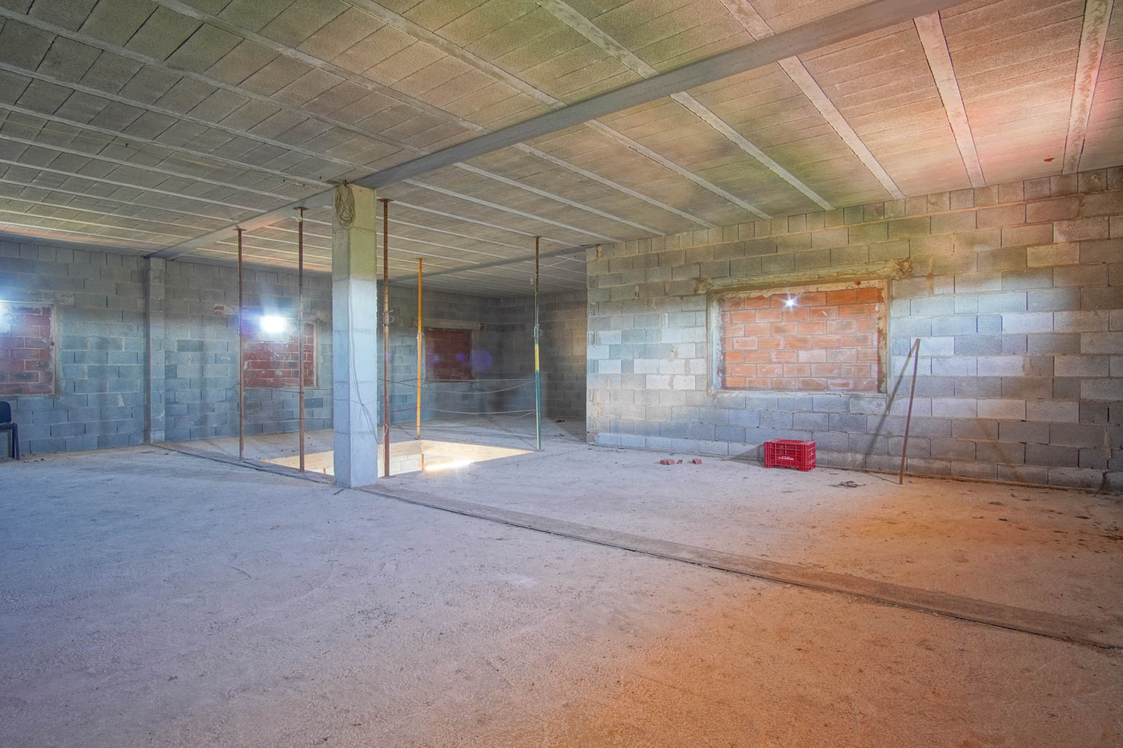 Open binnenruimte in ruwbouwstaat met wanden van betonblokken, stalen balken en een trapgat, klaar voor een gepersonaliseerde indeling.