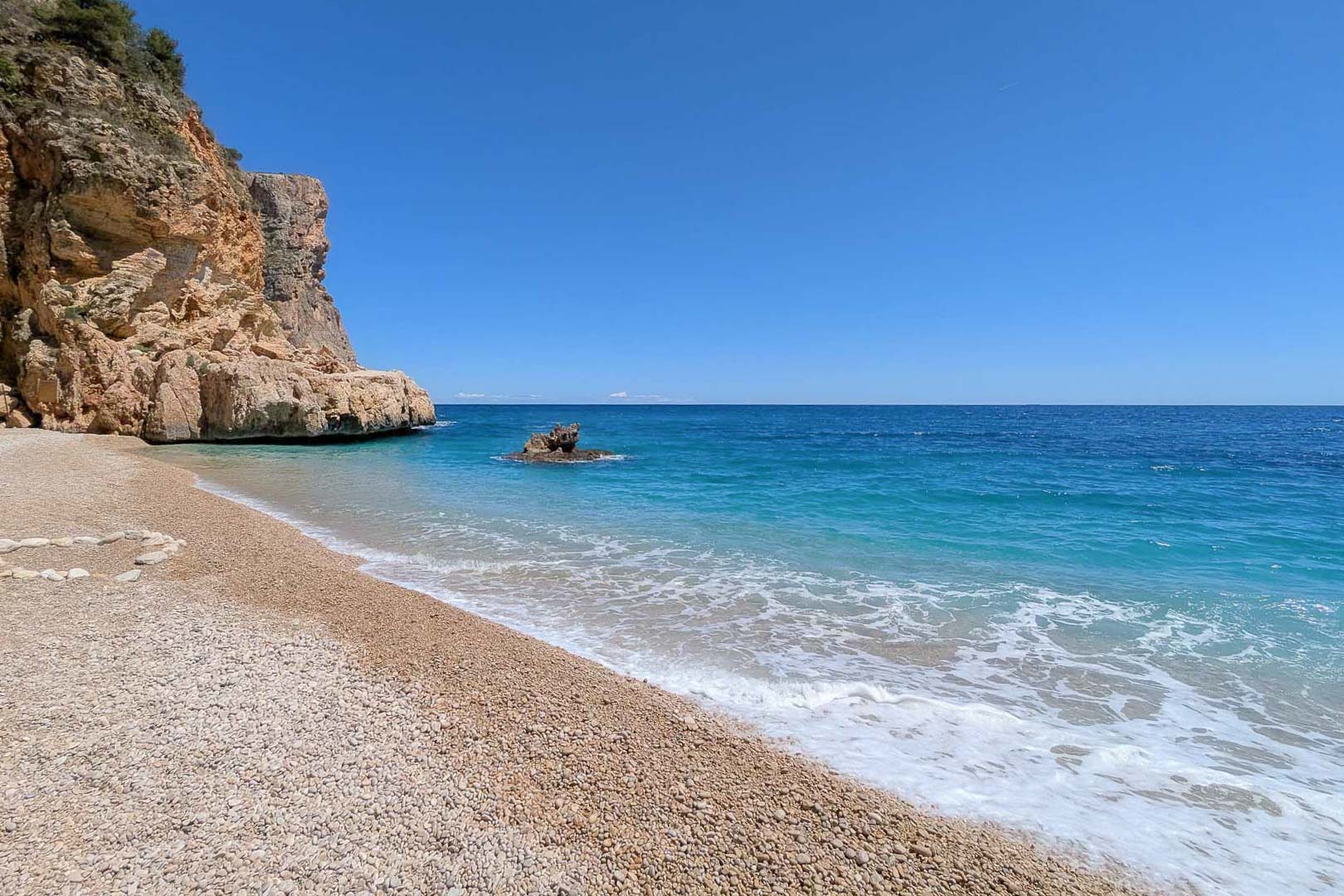 Kiezelstrand met turquoise water en kalkstenen kliffen, gelegen in de directe nabijheid van het perceel in El Portet, Moraira.