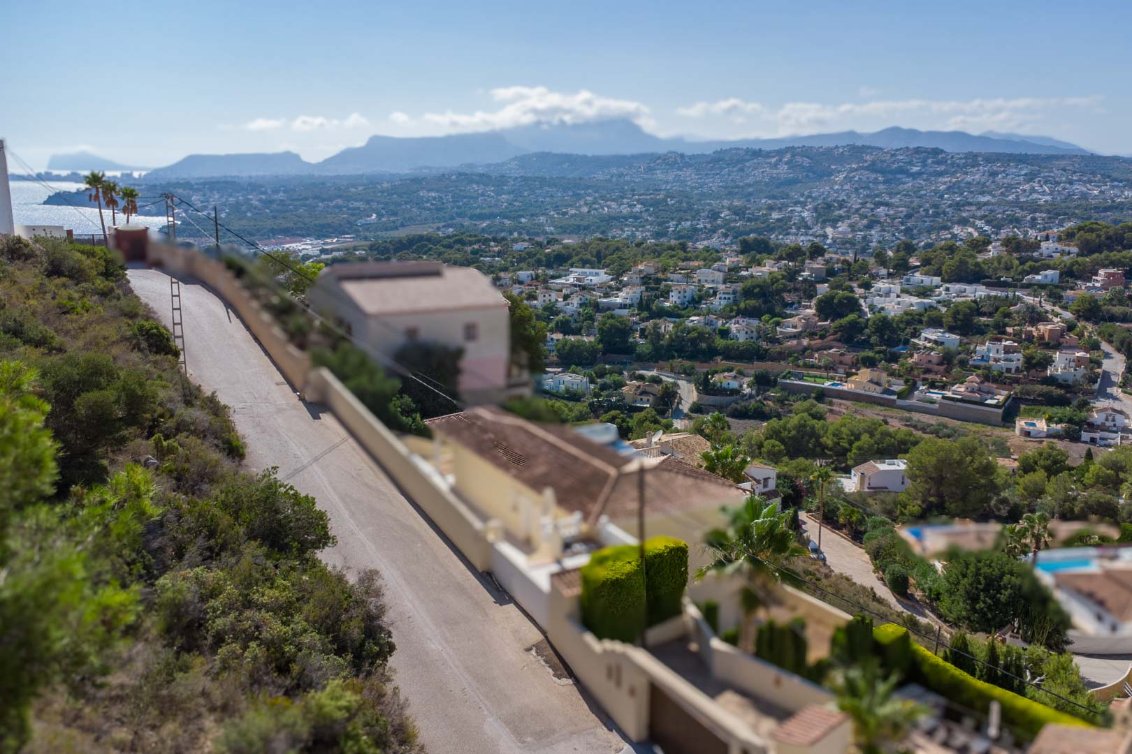 Verhoogd panoramisch uitzicht vanuit El Portet op de kust van Moraira en de Middellandse Zee, met bergketens zichtbaar aan de horizon.