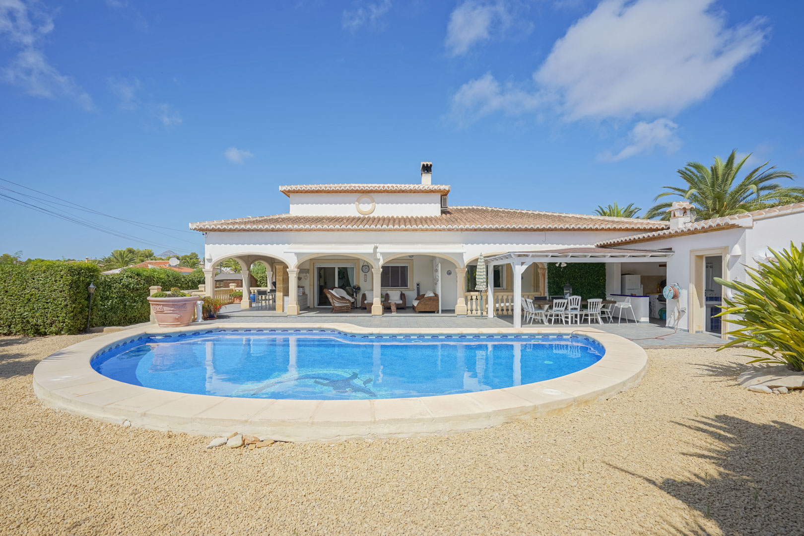 Uitzicht op het betegelde zwembad en het overdekte terras met bogen van een villa in Jávea.