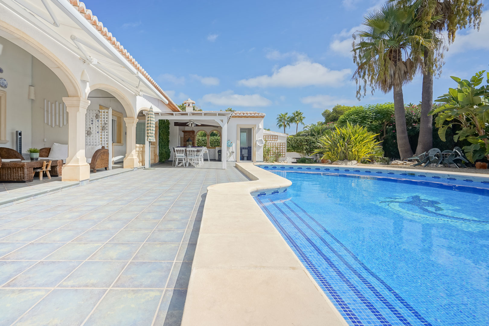 Uitzicht op het zwembad met blauwe tegels en terras met stenen kolommen in Jávea.
