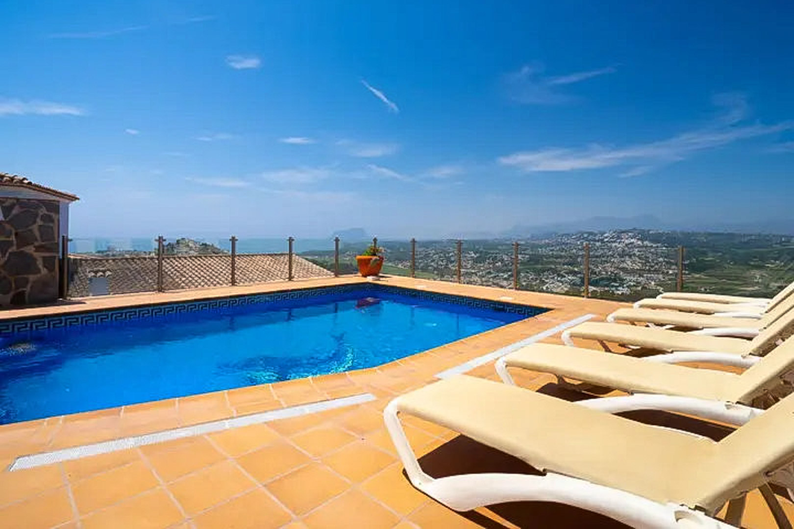 Buitenzwembad met Griekse mozaïekrand, terracotta zonneterras met ligbedden en glazen balustrade met panoramisch uitzicht op de Middellandse Zee en Moraira.