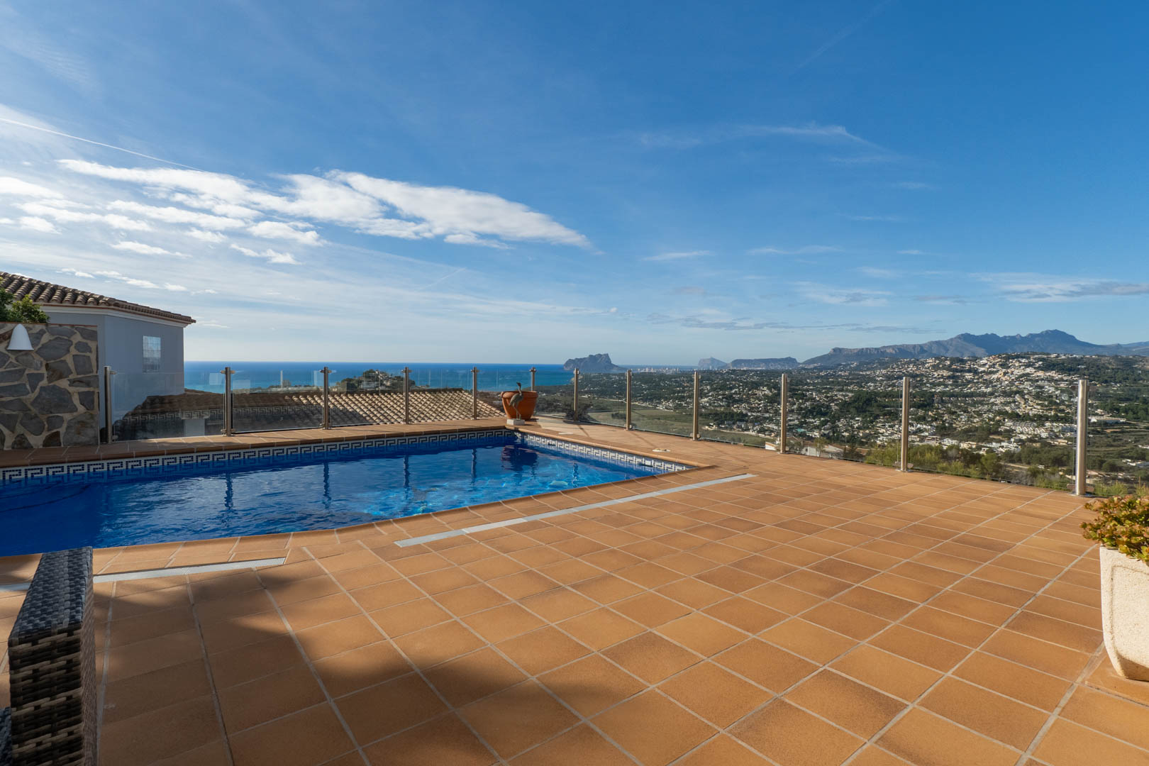 Terras met terracotta tegels en privézwembad, voorzien van glazen balustrades voor een onbelemmerd panoramisch uitzicht op de Middellandse Zee en de Peñón de Ifach.