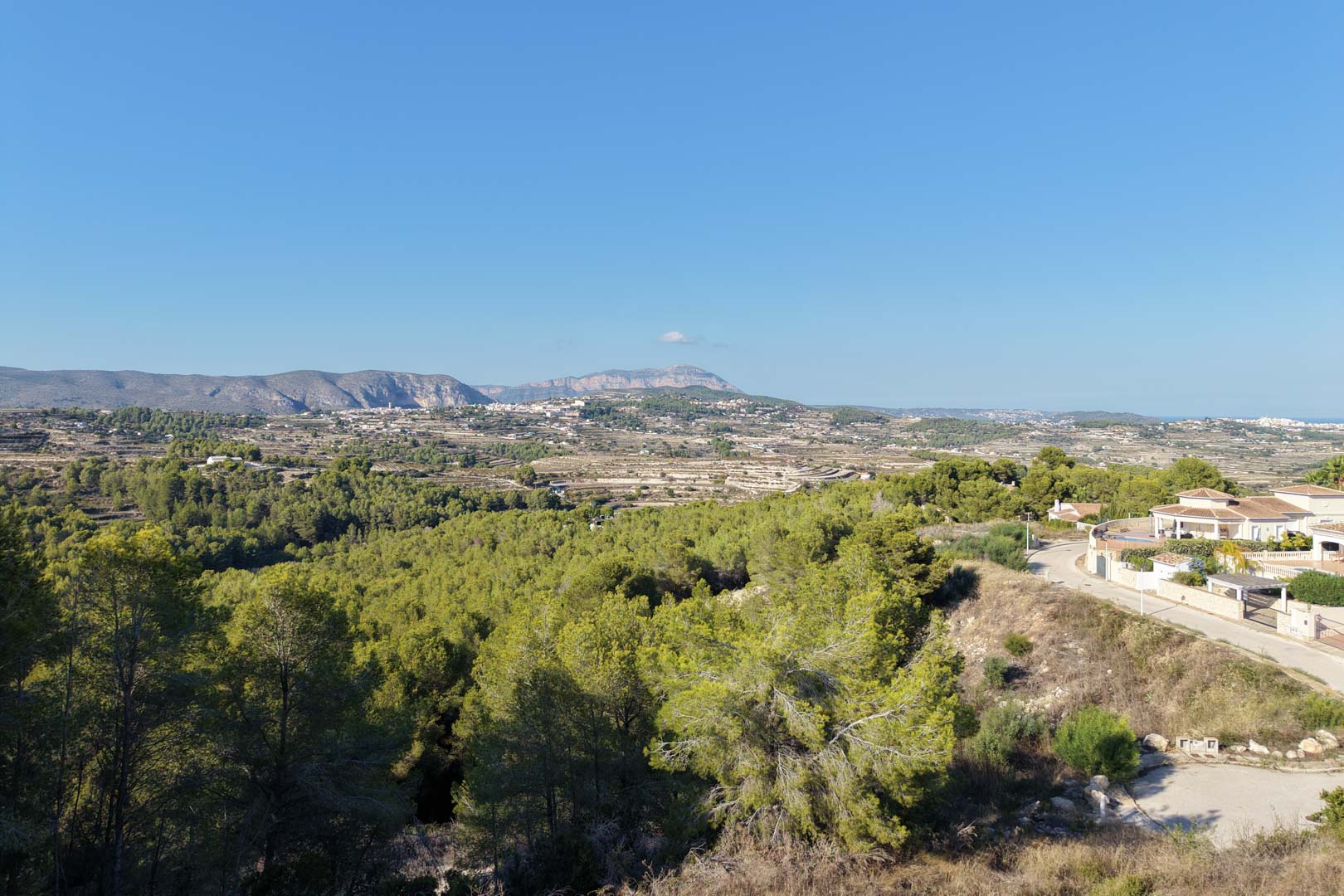 Verhoogd panoramisch uitzicht over de vallei en de bergen, omgeven door mediterrane dennenbossen en nabijgelegen villa's.
