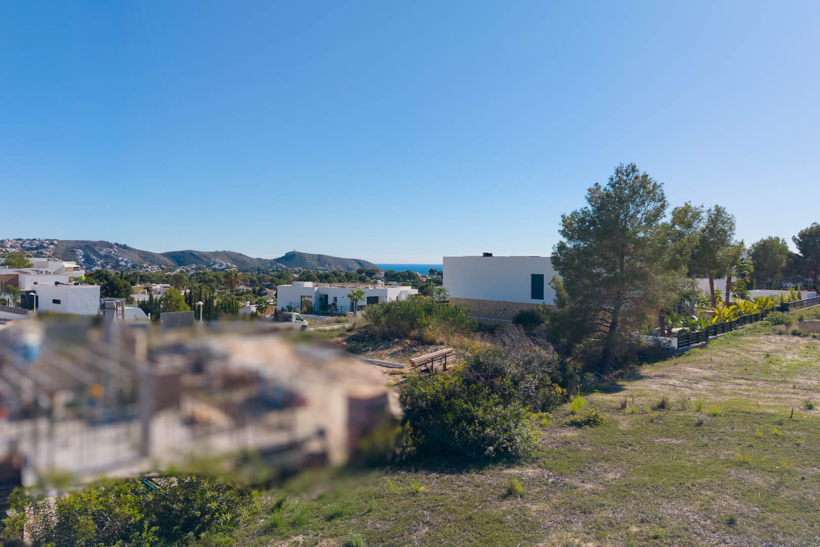 Panoramisch uitzicht vanaf het bouwperceel in El Tesoro, met vlak terrein, omliggende moderne villa's en vrij uitzicht over de vallei en de Middellandse Zee.