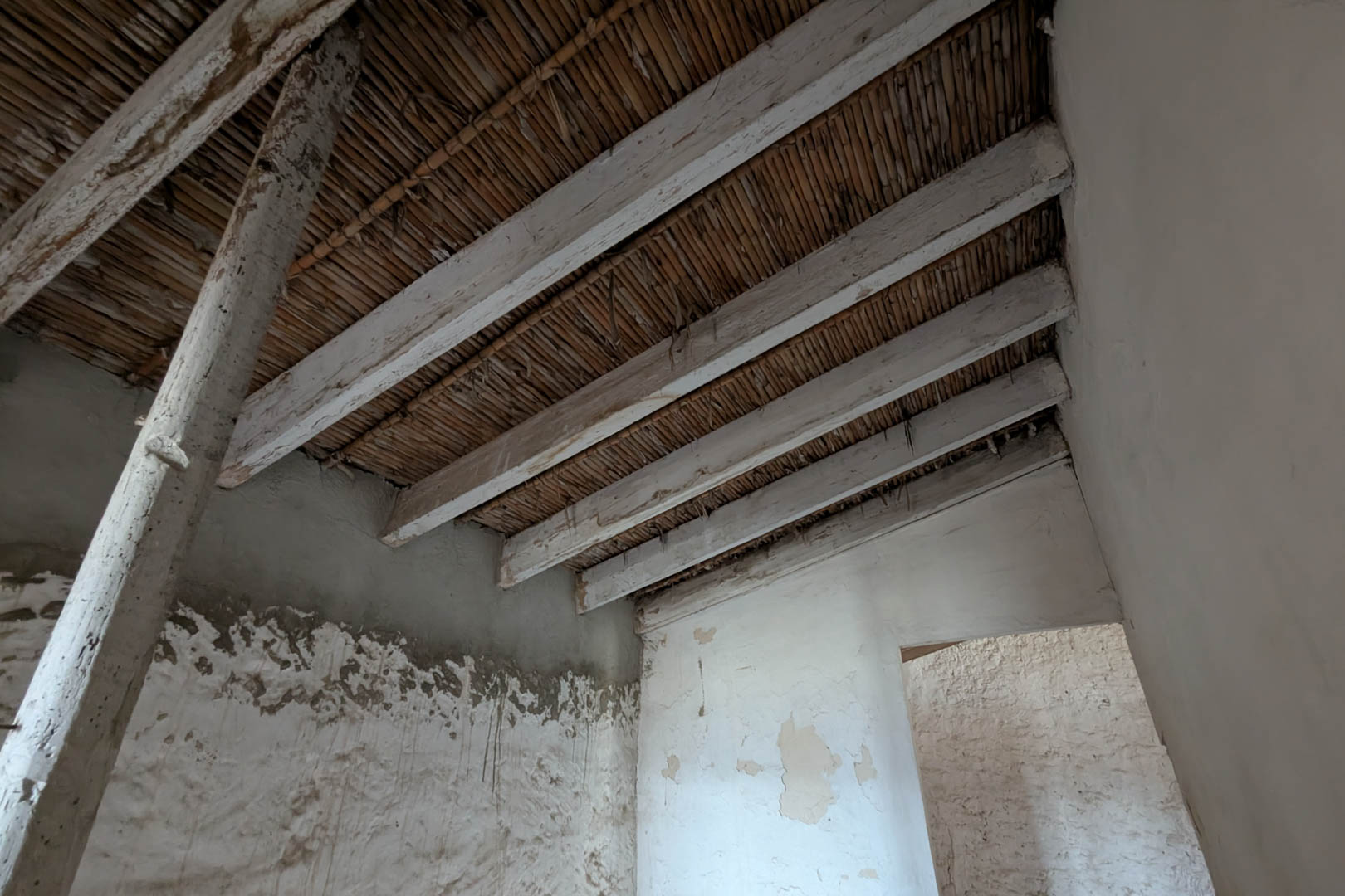 Interieurzicht met het originele rieten plafond en witgekalkte houten balken. De natuurstenen muren hebben hun traditionele kalklaag behouden.