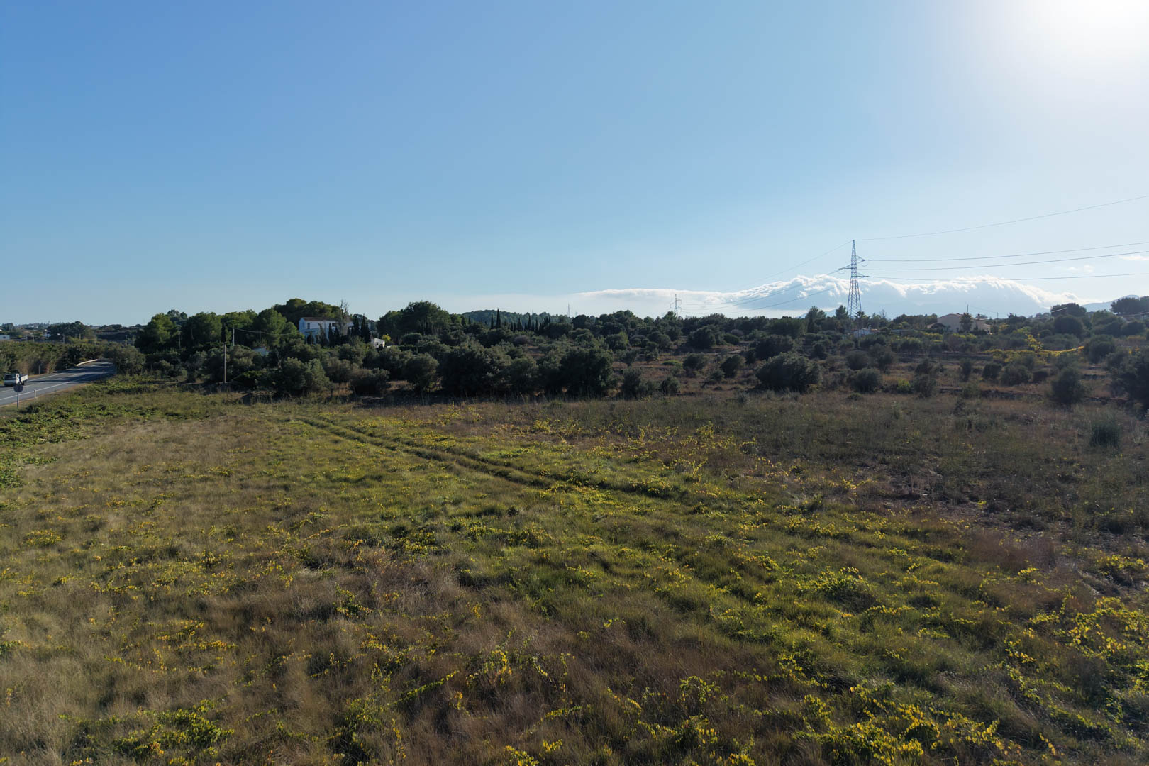 Panoramisch uitzicht op het uitgestrekte vlakke perceel in Teulada, omgeven door mediterrane vegetatie. Een veelzijdige buitenruimte met diverse ontwikkelingsmogelijkheden.