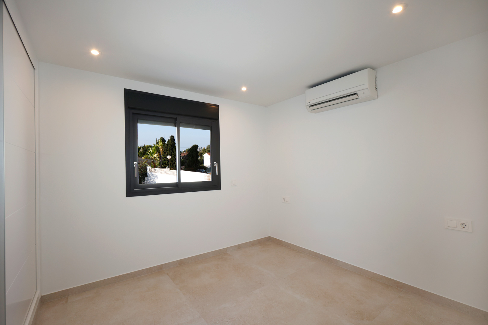 Lichte slaapkamer met porseleinen tegelvloer, inbouw-ledverlichting, airconditioning en Technal aluminium raamkozijn.