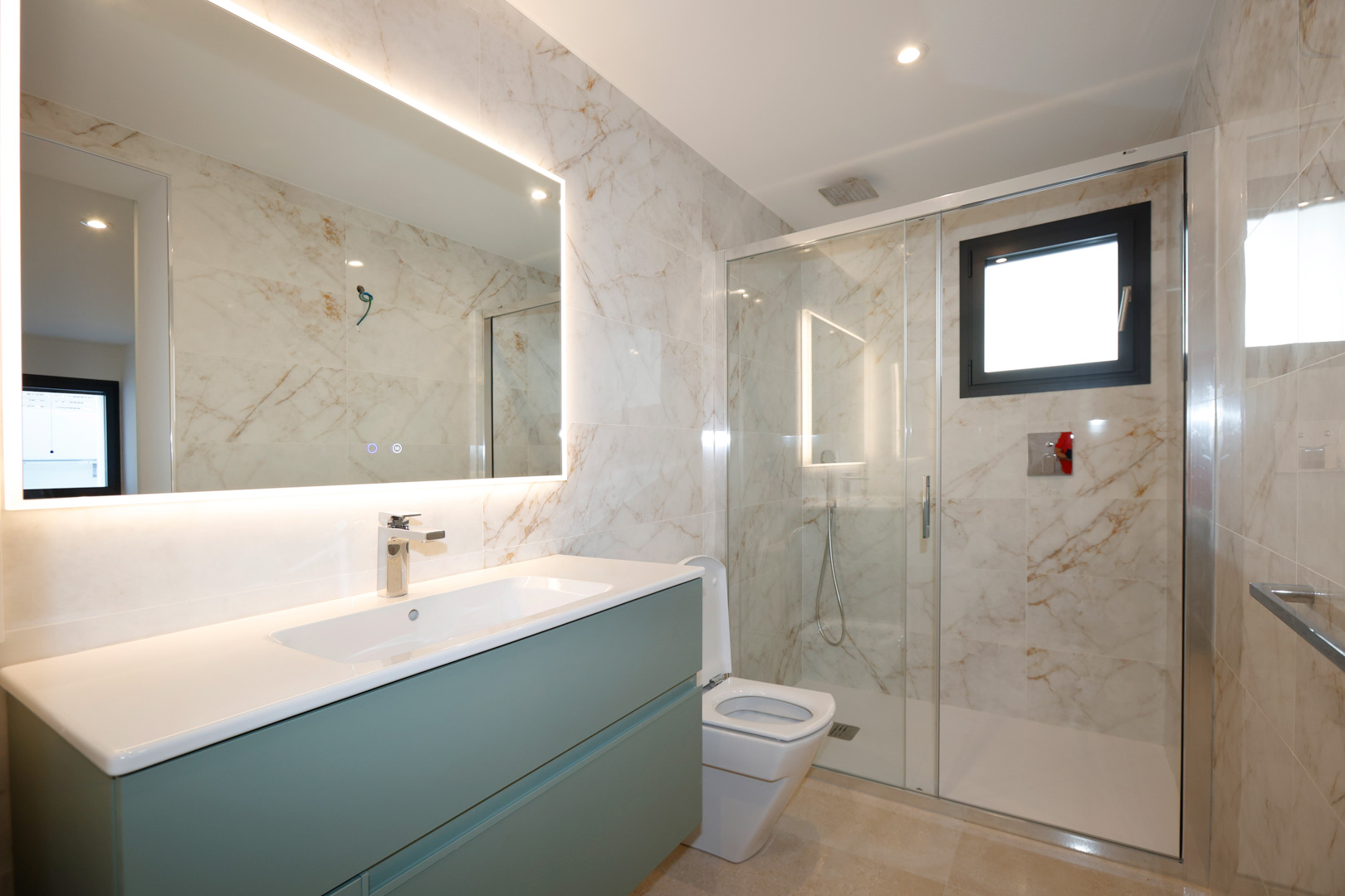 Moderne badkamer met een saliegroen wastafelmeubel, LED-verlichte spiegel en een inloopdouche met glazen wanden en tegels met marmerlook.