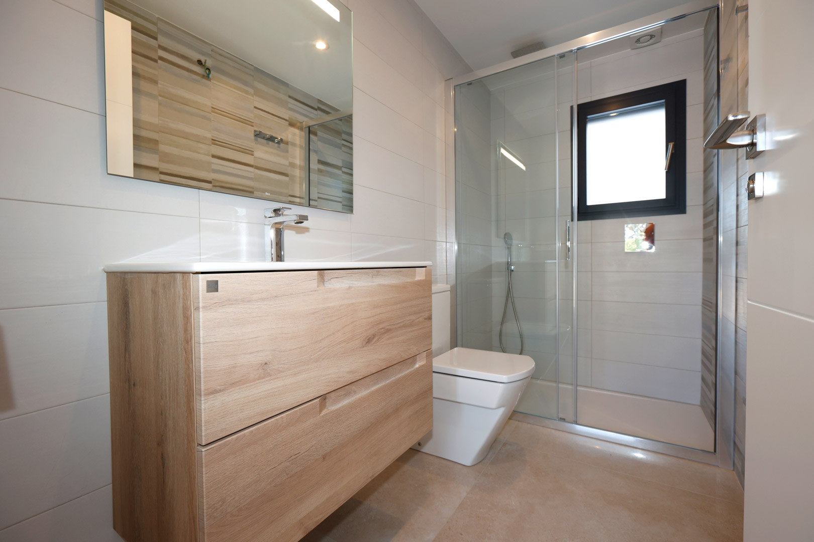 Moderne badkamer met houten wastafelmeubel, glazen douchewand en witte wandtegels. Afgewerkt met een porseleinen vloer en een zwart raamkozijn.