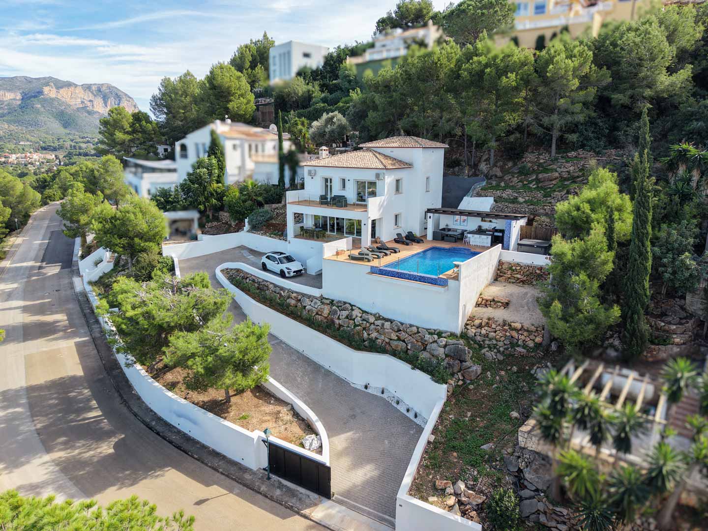 Luchtfoto van de mediterrane villa met privézwembad, terrassen op verschillende niveaus en buitenkeuken, gelegen op een hellend perceel met natuurstenen muren.