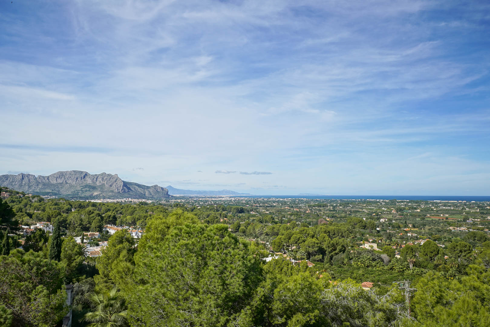 Verhoogd panoramisch uitzicht vanuit La Sella op het Montgó-gebergte, de groene kustvallei en de Middellandse Zee aan de horizon.