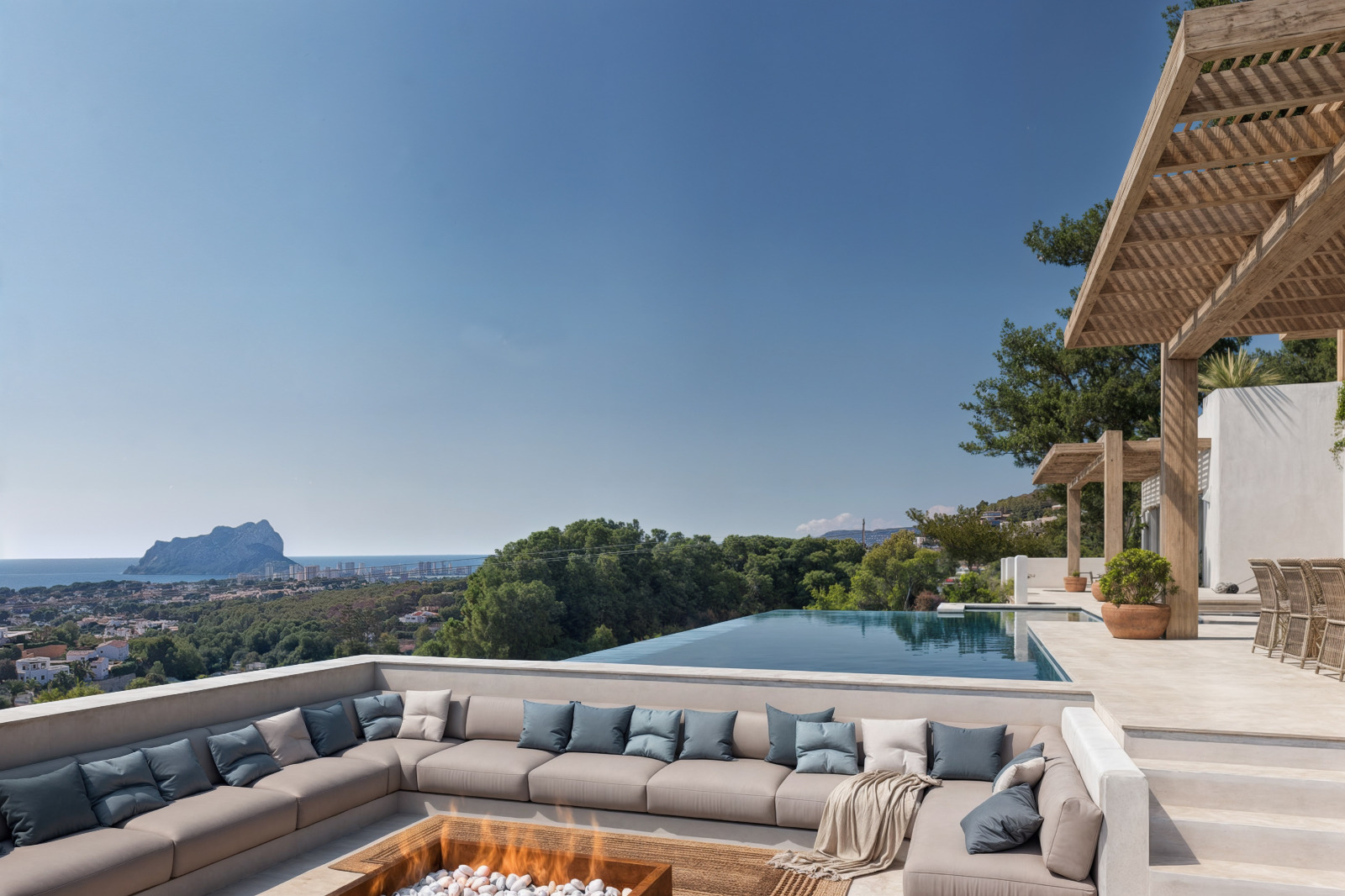 Verzonken zithoek met vuurkorf en overloopzwembad, voorzien van houten pergola's en panoramisch uitzicht op de Middellandse Zee en Calpe.