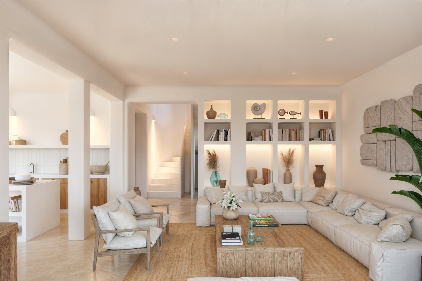 Woonkamer in Ibizastijl met verlichte nissen in de wand, een ruime hoekbank en een massief houten salontafel. De open ruimte biedt zicht op de trap en de aangrenzende keuken.