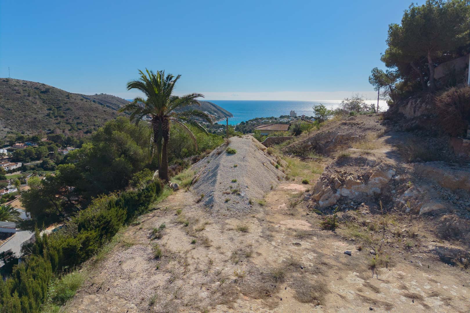 Panoramisch uitzicht vanaf het verhoogde perceel op de baai van El Portet, met het natuurlijke mediterrane landschap en weids zicht op de zee in Moraira.
