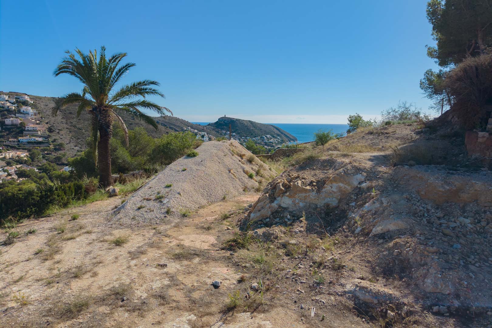 Verhoogd bouwperceel in voorbereiding met panoramisch uitzicht op de Middellandse Zee en de kustlijn van Moraira, omgeven door natuurlijke vegetatie.