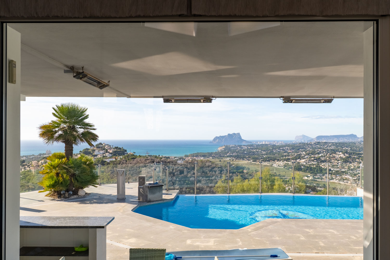 Uitzicht van binnen naar het privézwembad met uitzicht op zee en het landschap in Moraira.